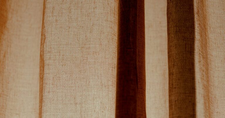 A backlit linen curtain in soft folds, warm daylight behind it