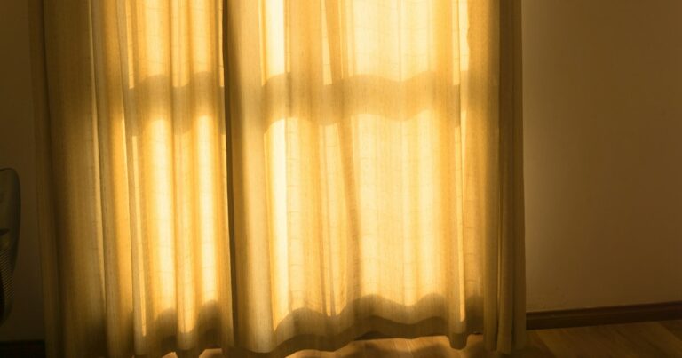Morning sunlight glowing through pale linen curtains onto a wooden floor