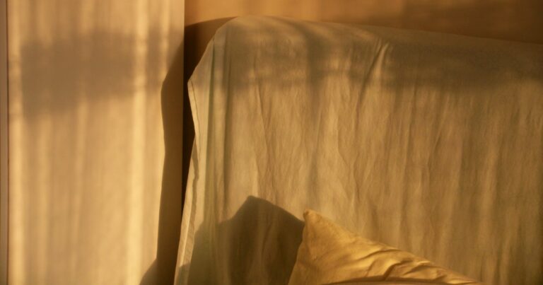Warm evening light and soft shadows across a linen-covered headboard and a pillow