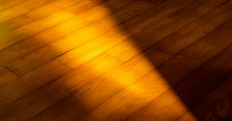 A band of warm golden sunlight falling across a wooden floor beside shadow