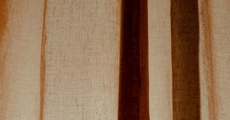 Folds of a warm brown linen curtain lit from behind