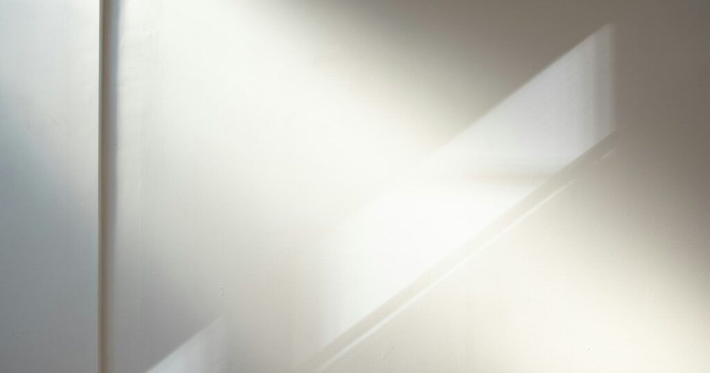 Soft sunlight falling in a diagonal band across a pale wall