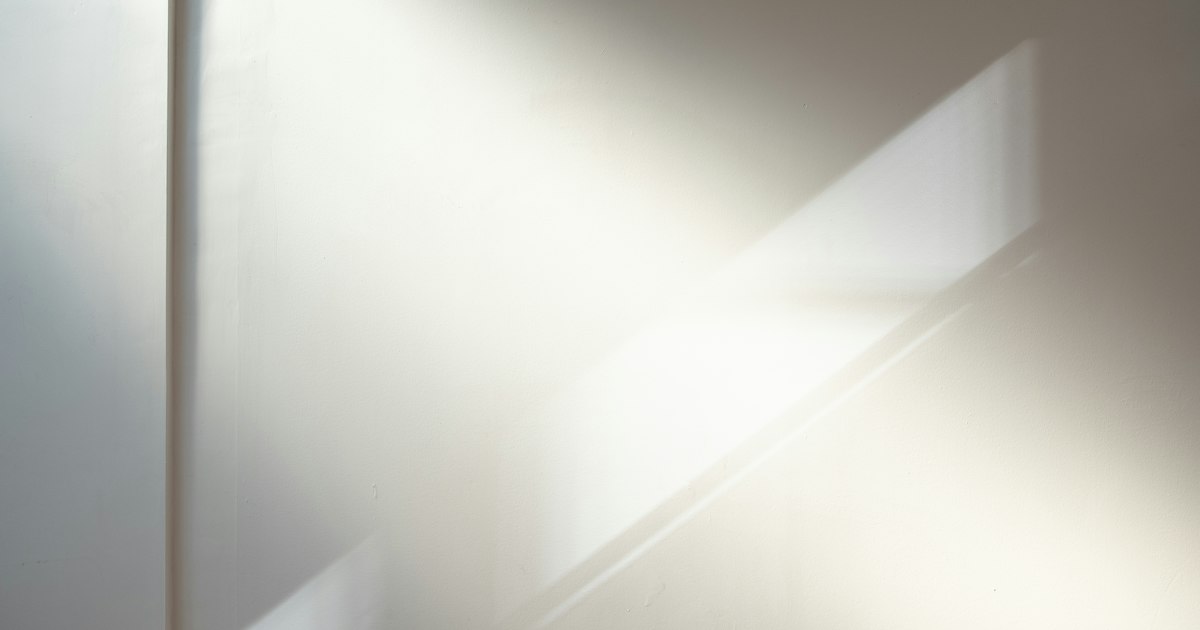 Soft sunlight falling in a diagonal band across a pale wall