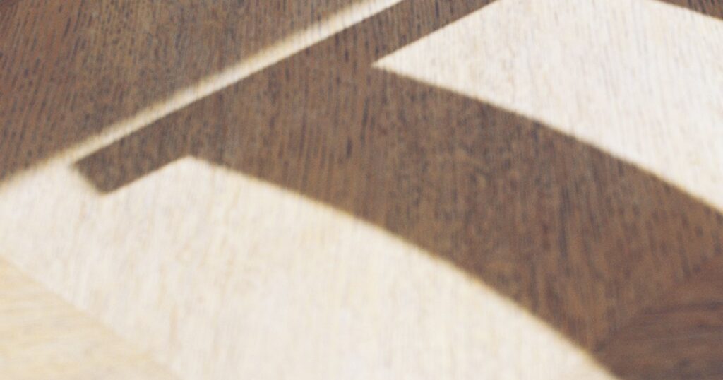 Angled sunlight casting a sharp shadow shape across a pale wooden floor