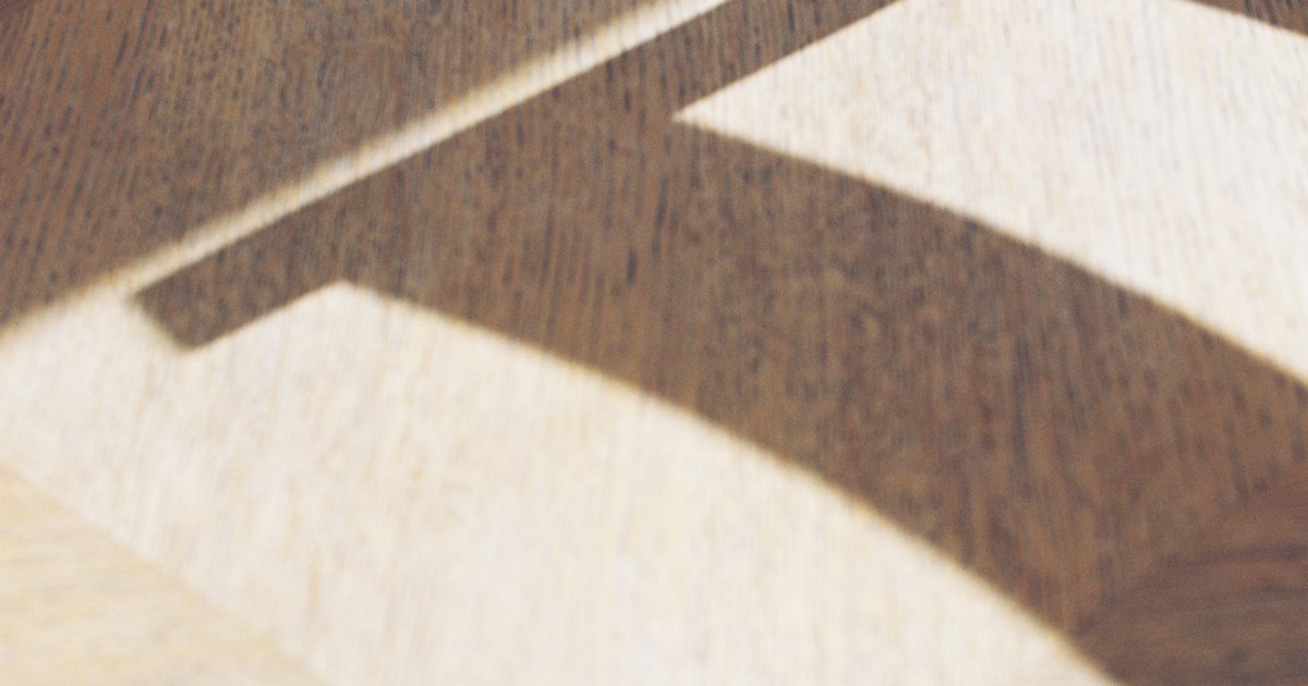 Angled sunlight casting a sharp shadow shape across a pale wooden floor