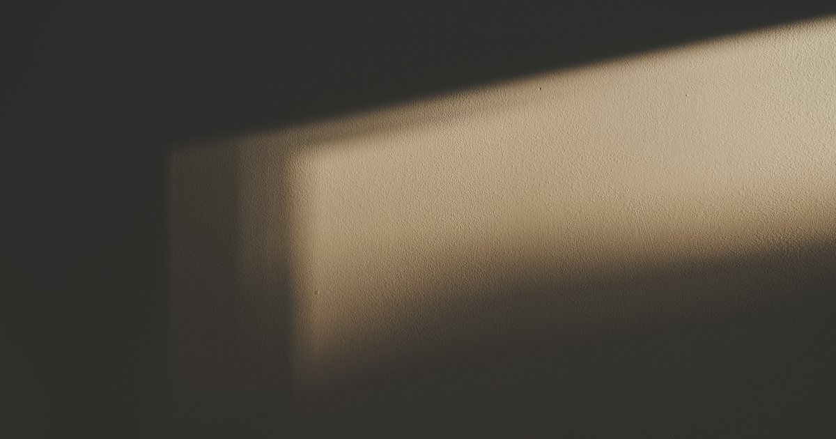 A soft band of window light across a quiet plain wall