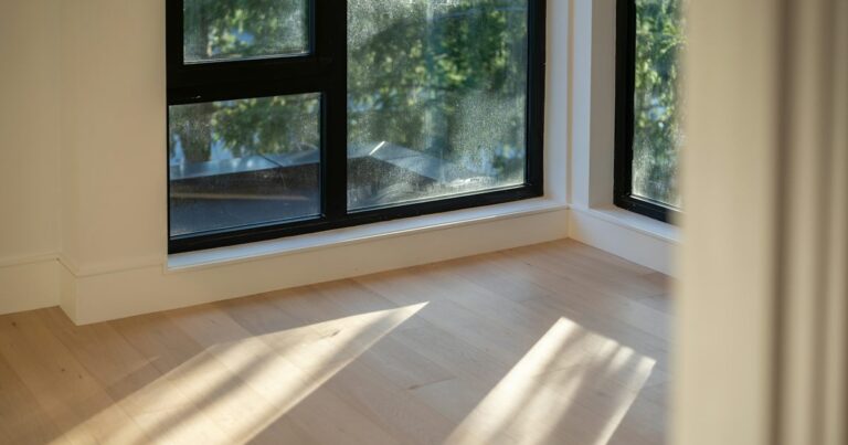 Late sunlight falling across pale wooden floorboards beside a window