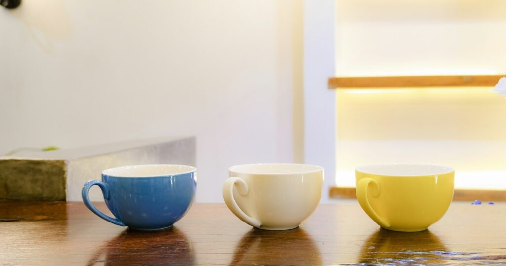 Blue, white and yellow cups in a row on a wooden table