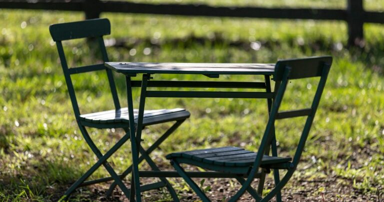 Two folding chairs at a small table on sunlit grass