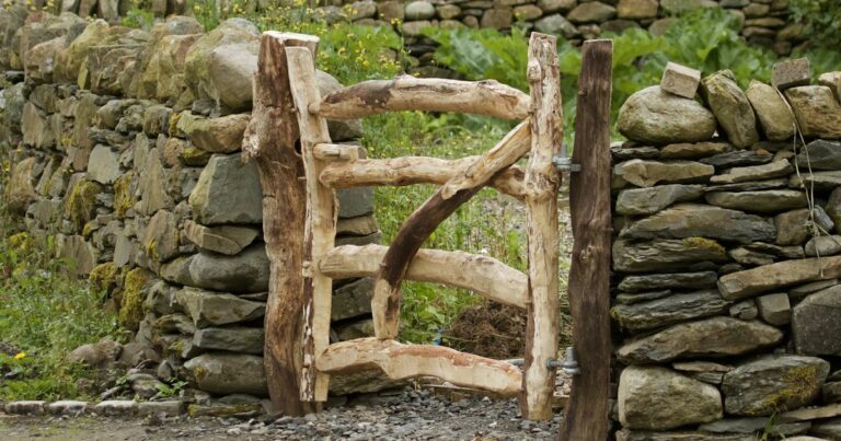 A rustic wooden gate set in a dry stone wall, with a green garden visible beyond it